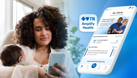 A parent holding an infant while viewing the AmplifyHealth app on a smartphone, illustrating mobile access to healthcare services.