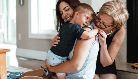 Mother and grandmother embracing special needs toddler