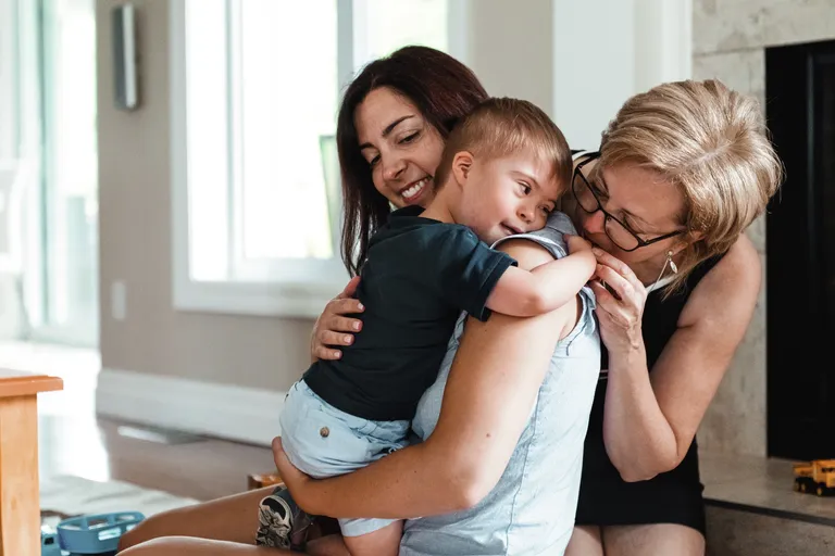 Mother and grandmother embracing special needs toddler