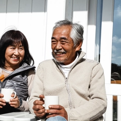 Man and Woman sit outdoors enjoying a cup of coffee