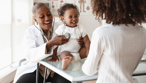 Baby laughing with female doctor and mom