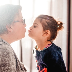 Grandmother giving a kiss to her young granddaughter