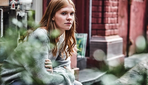 Young woman sitting at house entrance