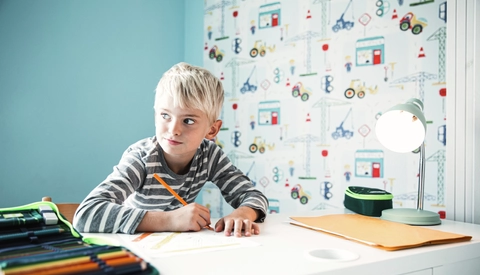 Boy doing homework at desk in children's room