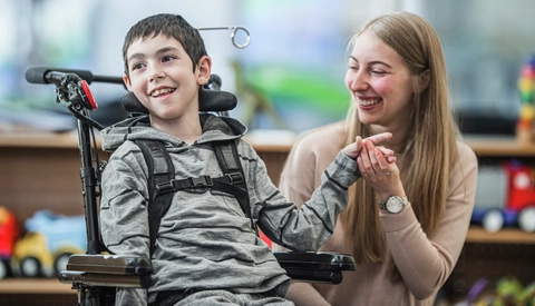 A boy with special needs in  classroom with an assistant