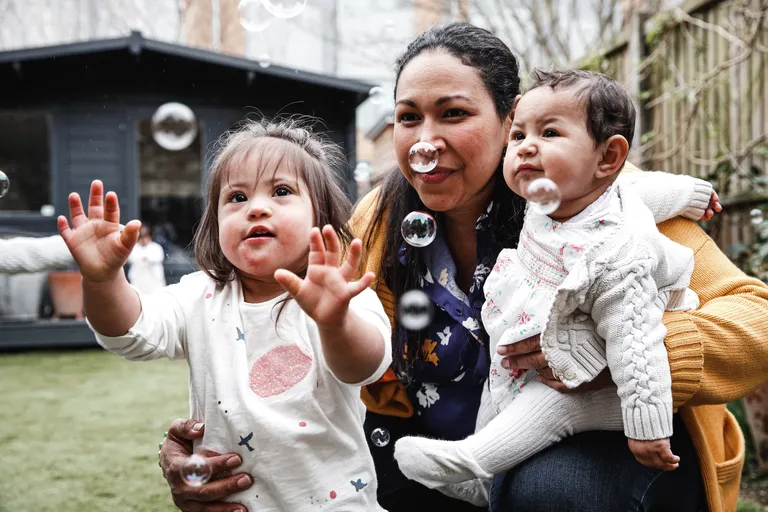 Mother watching bubbles in garden with two daughters