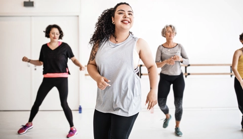 Young woman learning dance moves in fitness class