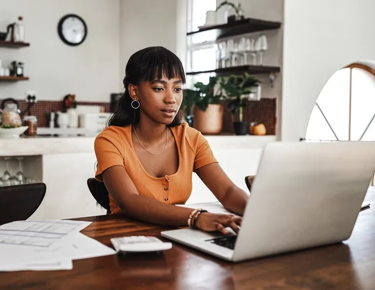 Young woman sitting with her laptop and paperwork at home