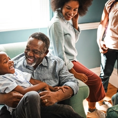 Happy grandfather laughing with grandson on sofa
