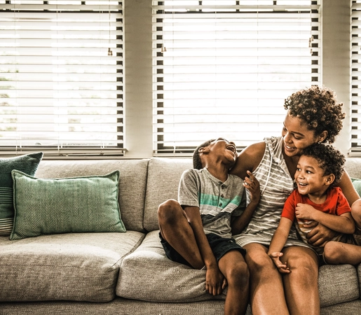 Mother playing with young sons on couch