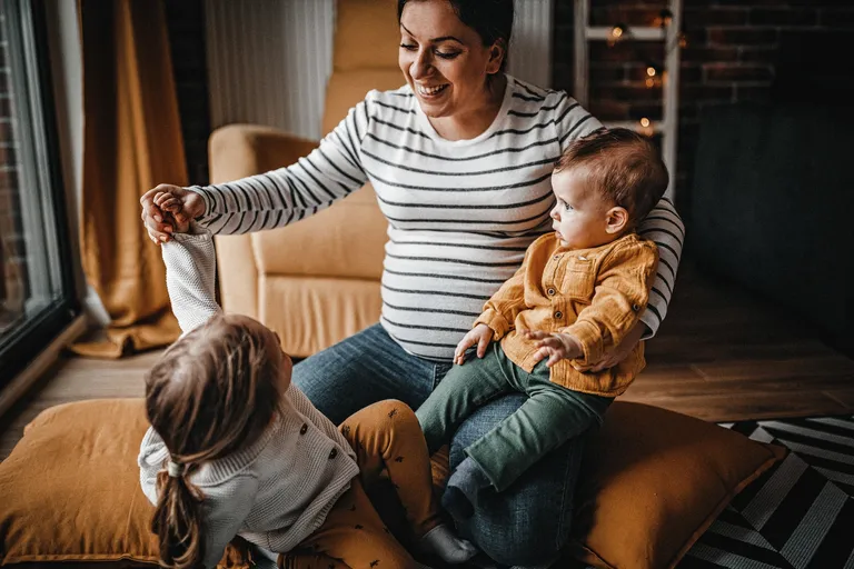 Mother sitting with two young children indoors