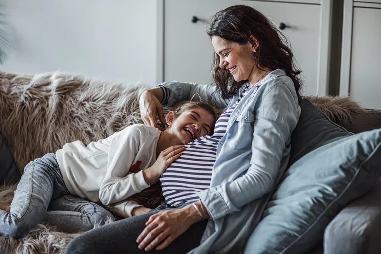 Daughter hugging pregnant mother