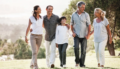 Multi generation family holding hands and walking in the park