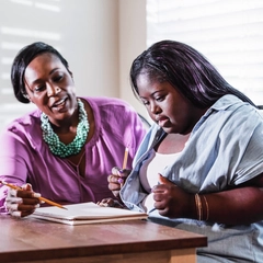 Teenager with Down syndrome working on a document with her mother
