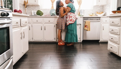 Grandmother kissing grandchild in kitchen at home