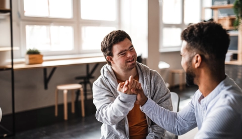 Young man with Down syndrome celebrating success with his mentoring friend