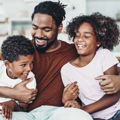 Father sitting hugging his two children.