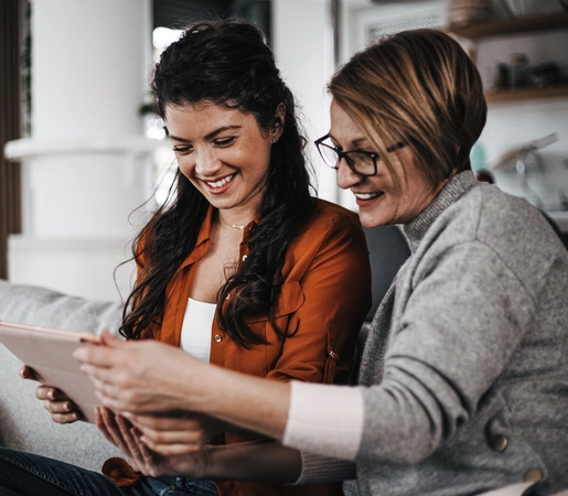 Mother and daughter having fun watching some funny content on their tablet