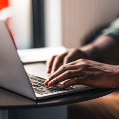 Doctor's hands typing on a laptop keyboard as they search for digital resources online.