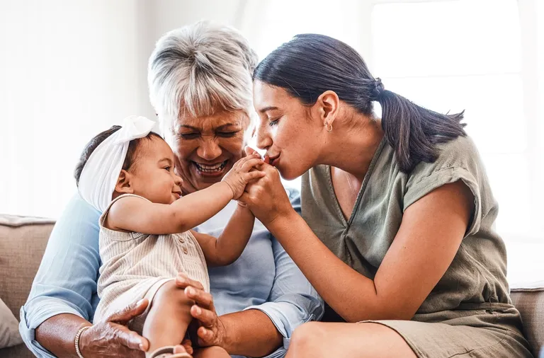 Mature woman bonding with her daughter and granddaughter on the sofa