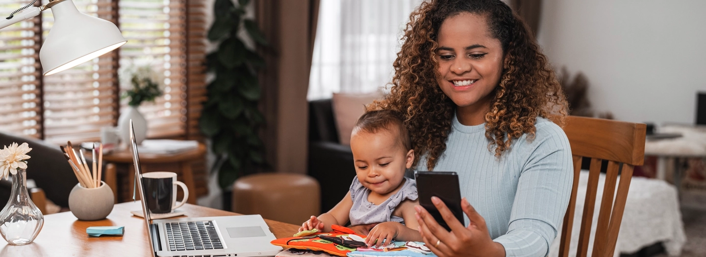 Mother holding young child while looking at smartphone