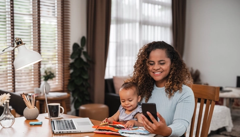 Mother holding young child while looking at smartphone