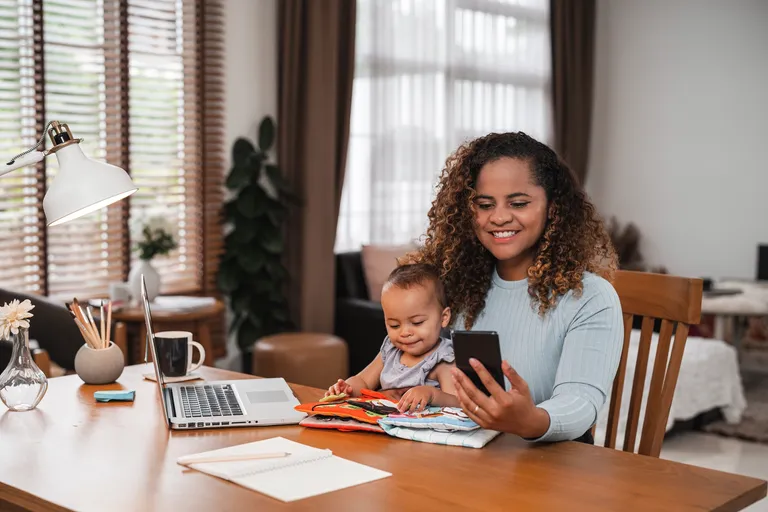 Mother holding young child while looking at smartphone