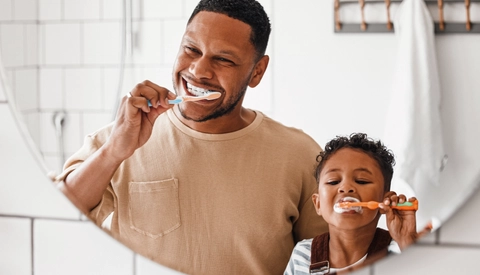 Happy father and son brushing their teeth together