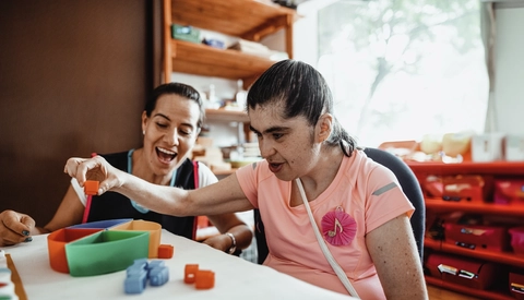 Teacher working with woman with Down Syndrome.