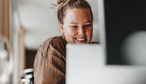 Happy female business professional working on laptop at office