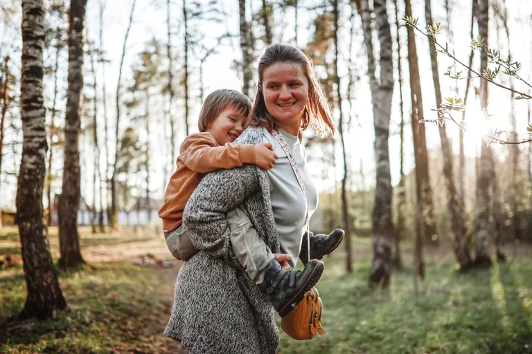 Woman carrying her son on back while walking in nature