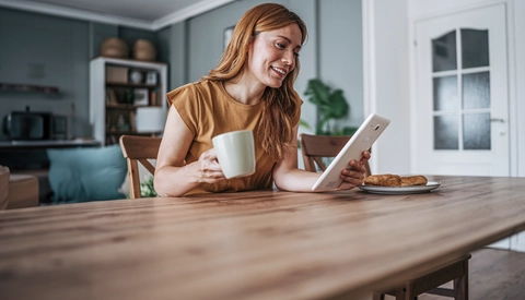 A woman on her ipad drinking a coffee