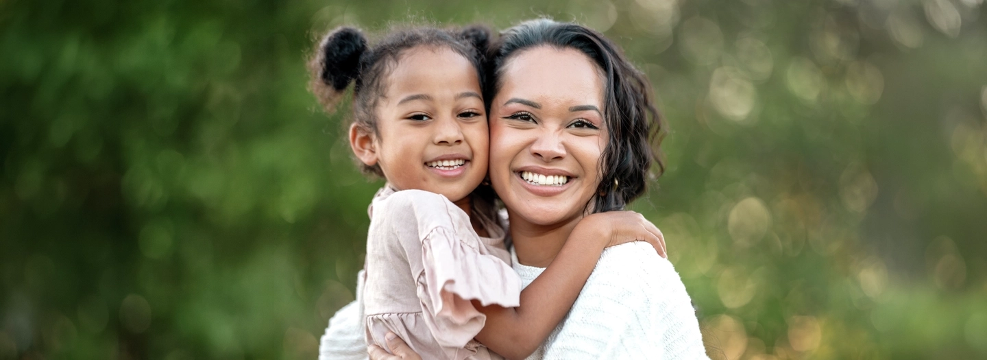 Smiling Mother and Daughter Hugging in an Outdoor Setting