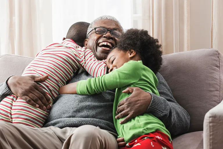 Older man hugging grandchildren on sofa