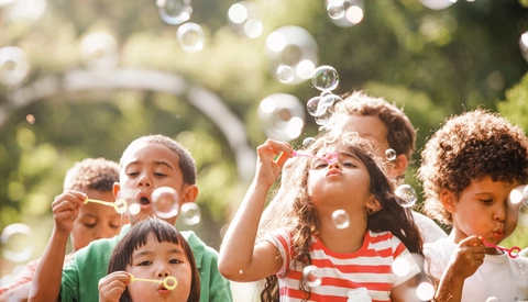 Children outdoors blowing bubbles