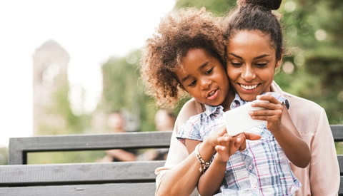 Mother and daughter using smartphone in the park