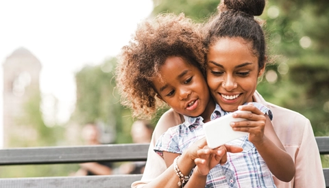 Mother and daughter using smartphone in the park
