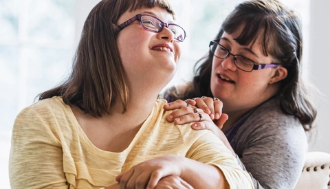 Two friends sitting on chairs at home