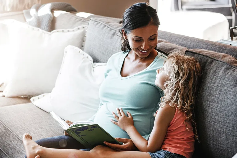 Pregnant woman spending time with her daughter at home