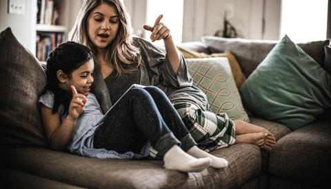Mother and daughter using tablet on couch