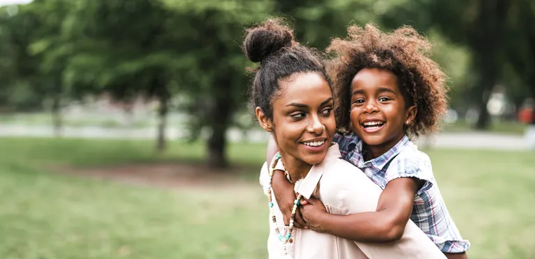 Woman with daughter smiling on her back