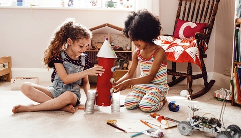 Two children working together to build a toy rocket ship