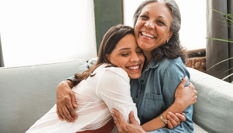 Mother and daughter hugging on sofa