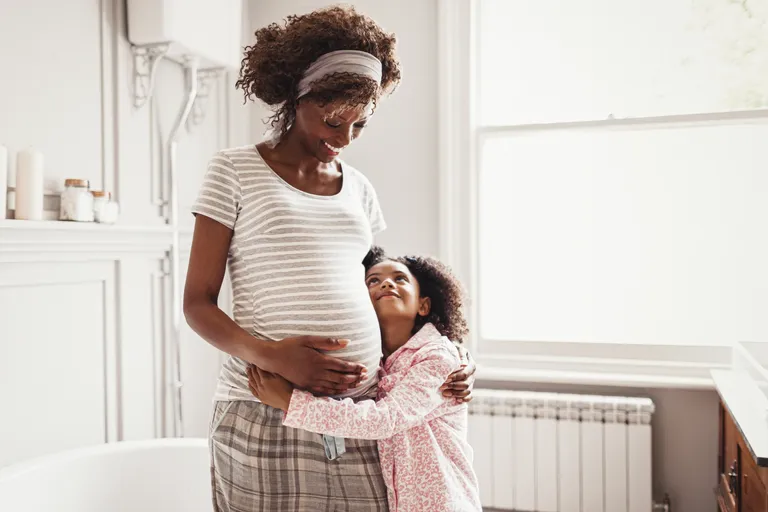 Affectionate daughter hugging pregnant mother