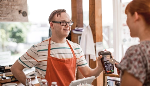 A young man at a grocery store assisting a customer