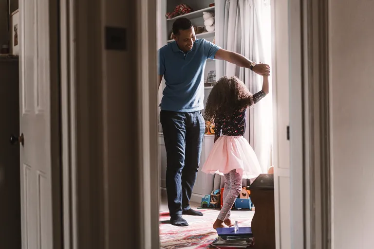 Father dancing with daughter in bedroom