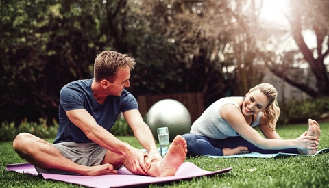 Two people stretching on yoga mats