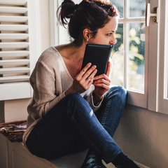 Relaxed woman reading a book near the window
