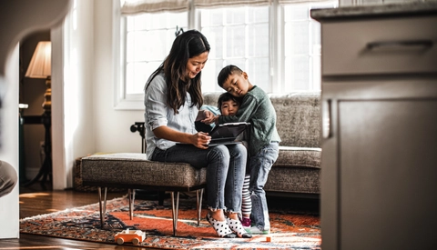 Mother using tablet at home with children present