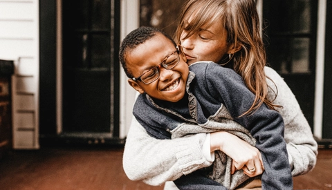 A mother and her son smiling, laughing and cuddling on the front porch